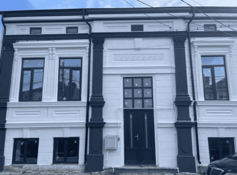 Clădire renovată cu fațadă alb-negru și ferestre mari, stil clasic, în centrul orașului.