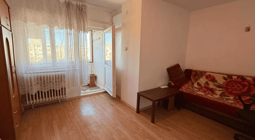 Ferestre cu perdele în cameră cu vedere spre oraș, interior simplu și confortabil.