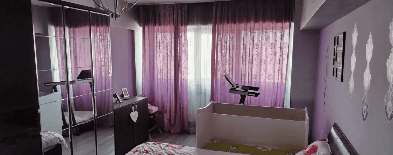 Camera de dormit cu perdele violet și mobilier modern pentru confort și relaxare.