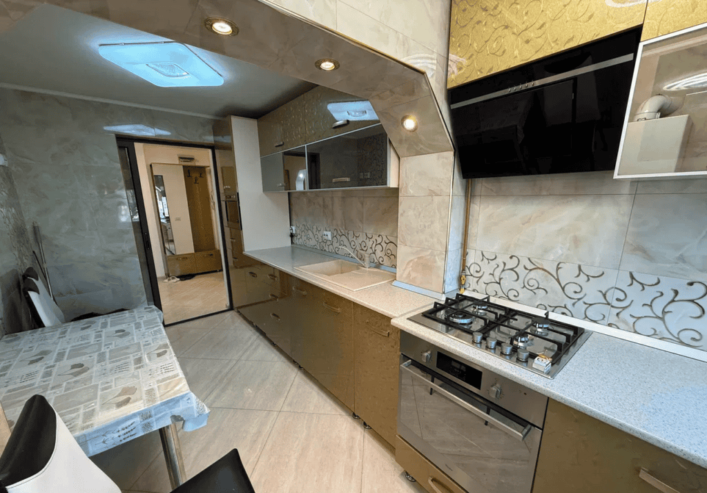 Bucătărie modernă cu plită și mobilier elegant, ideal pentru locuințe confortabile.