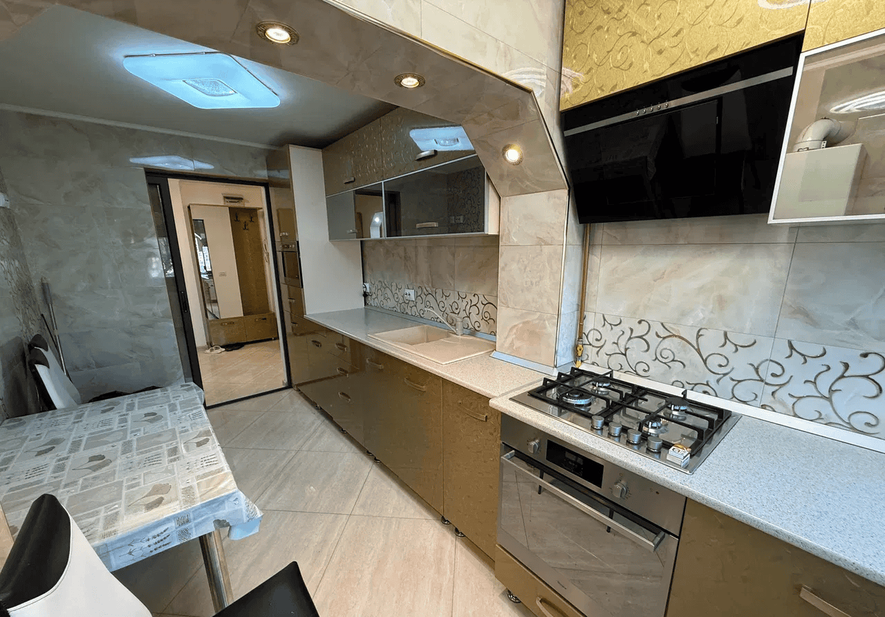 Bucătărie modernă cu plită și mobilier elegant, ideal pentru locuințe confortabile.