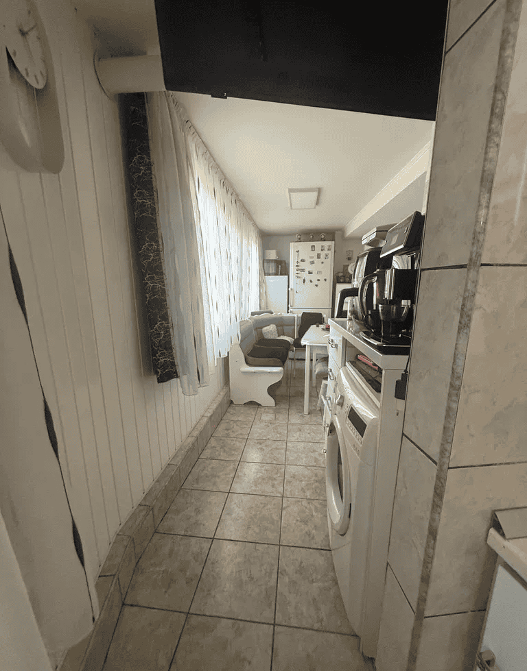 Bucătărie și living spațios într-o casă de vacanță, cu electrocasnice și mobilier confortabil.