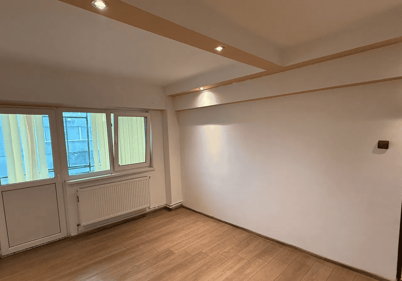 Spațiu de locuit luminos cu ferestre mari și podea din lemn.