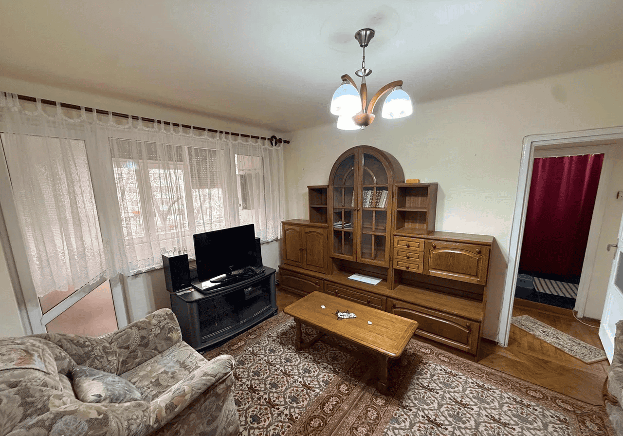 Camera de zi cu mobilier tradițional și televizor, ideală pentru relaxare.