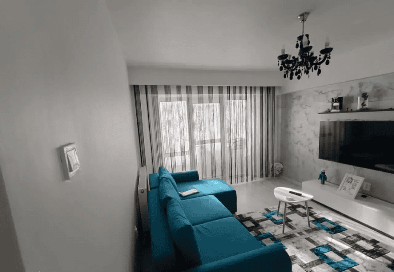 Camera de zi modernă cu canapea albastră, decor elegant și ferestre mari cu draperii.