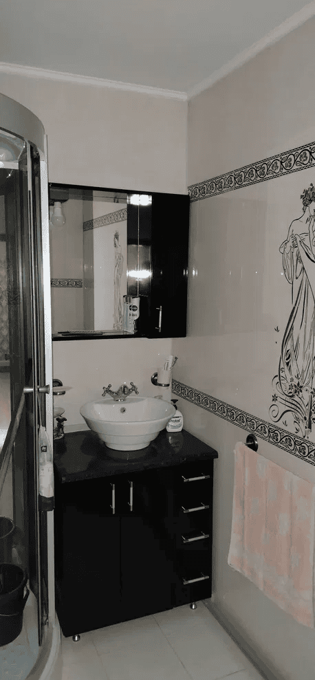 Baie modernă cu mobilier negru și decor artistic pe perete.