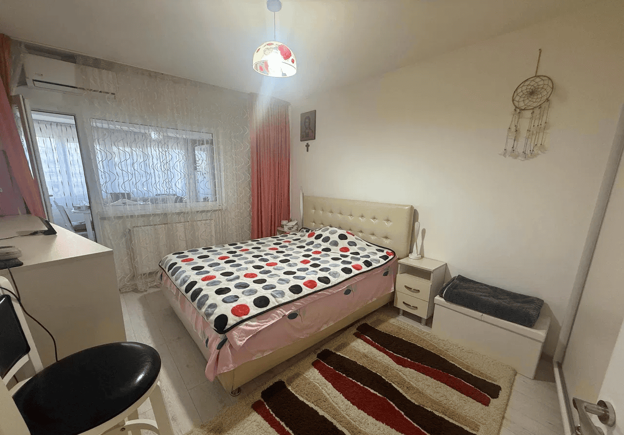 Pat dublu în dormitor cu decor minimalist și mobilier funcțional.