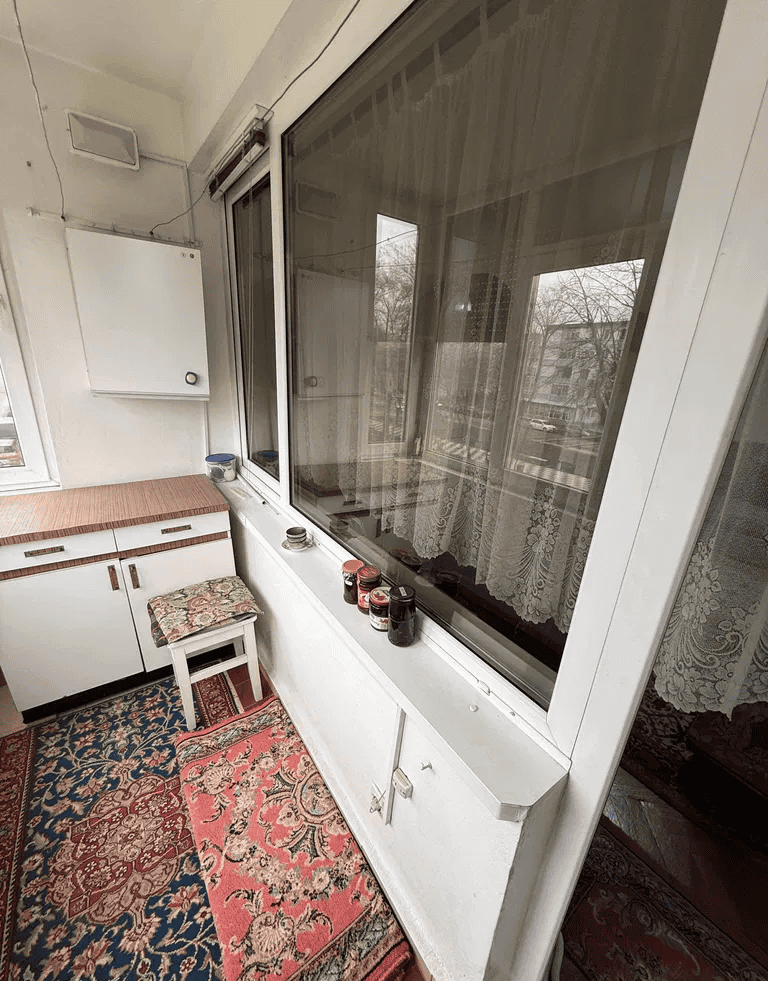 Ferestre mari cu draperii decorative și vedere spre balcon.