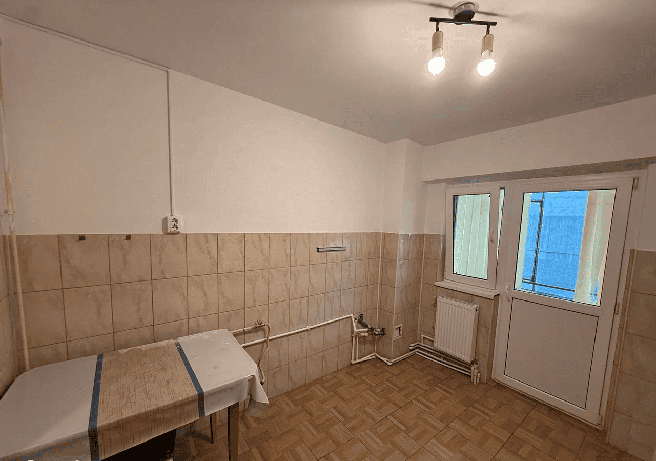 Camera de locuit cu ferestre mari și acces pe balcon.