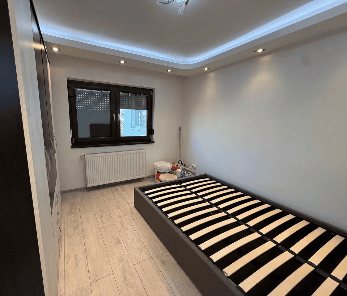 Pat de dormitor modern cu design minimalist și lumină ambientală subtilă.