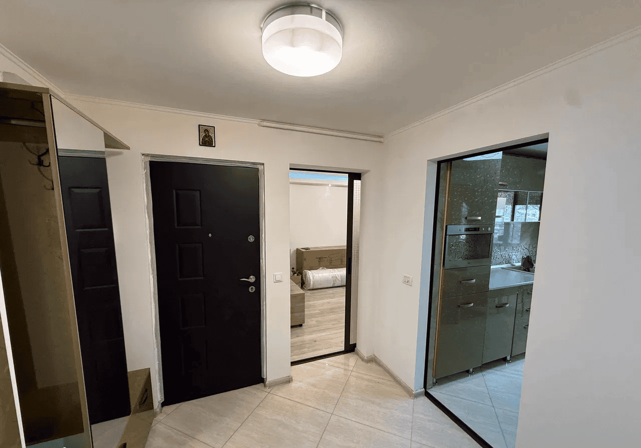 Intrare în apartament cu bucătărie modernă și spațiu luminos.